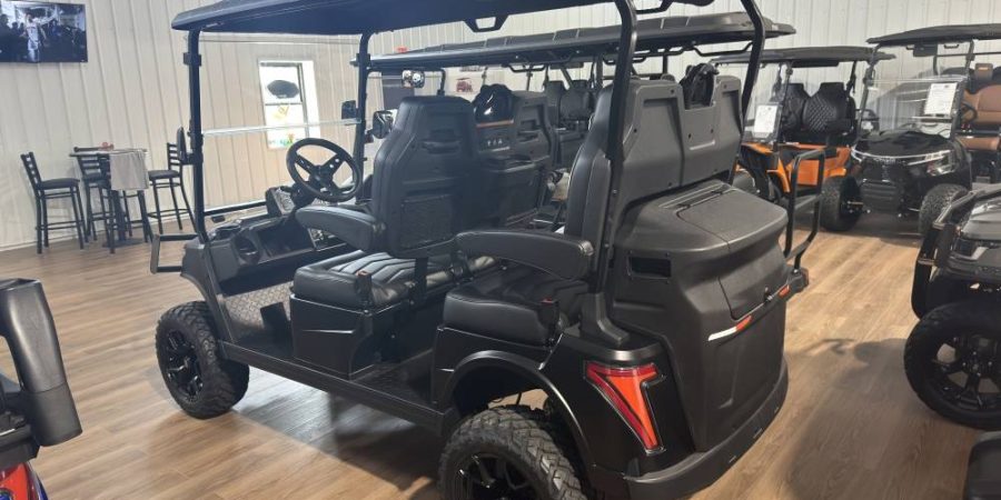 Premium black lifted golf cart with off-road wheels, upgraded seating, extended canopy, and rear storage compartment showcased in a dealership.
