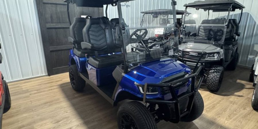 Blue 4-passenger Breezy electric golf cart with black diamond-pattern seating, rugged brush guard, windshield, and heavy-duty wheels, photographed in the Hurricane Golf Carts showroom.