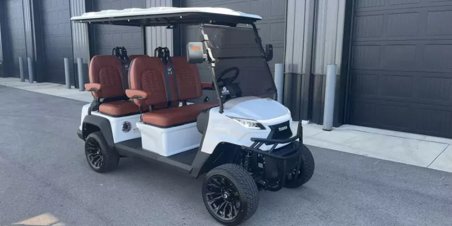 White Voyager electric golf cart with premium brown diamond-stitched seats and black off-road wheels parked outside Hurricane Golf Carts.