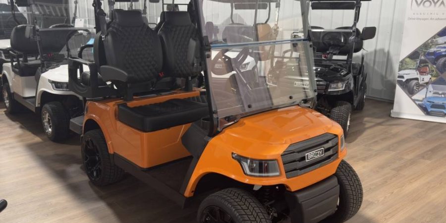Orange Breezy 2-passenger electric golf cart with black diamond-stitched seats and alloy wheels in the Hurricane Golf Carts showroom in Winchester, KY.