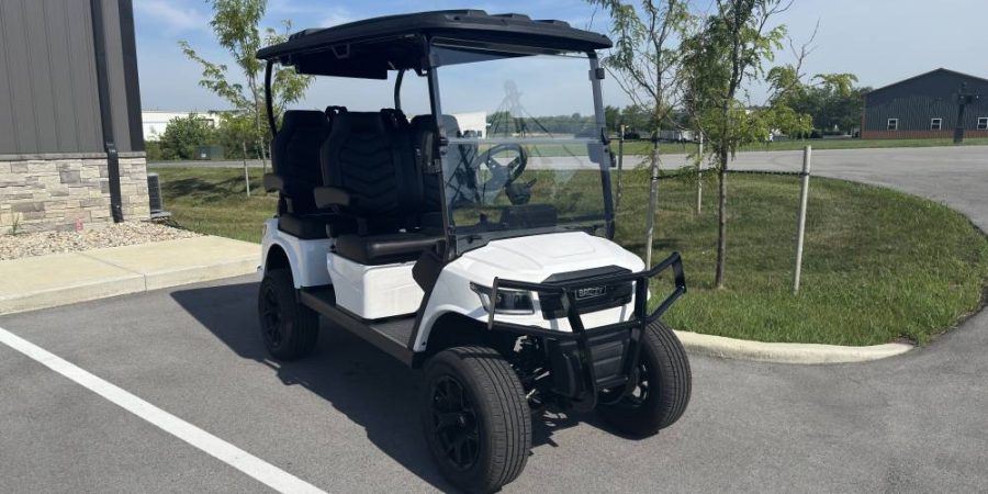 White Breezy 4-seat electric golf cart with black contoured seats, fold-down armrests, windshield, and off-road wheels, pictured in outdoor lot at Hurricane Golf Carts.