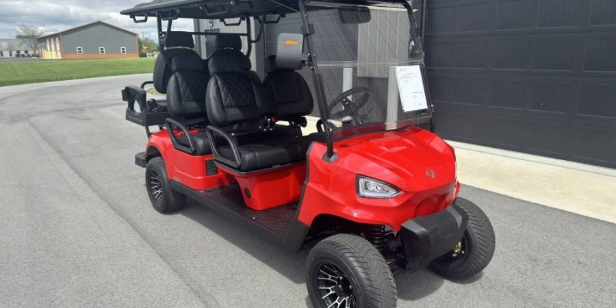 Red Voyager 6-passenger electric golf cart with black diamond-stitched seats parked outside Hurricane Golf Carts in Winchester, KY