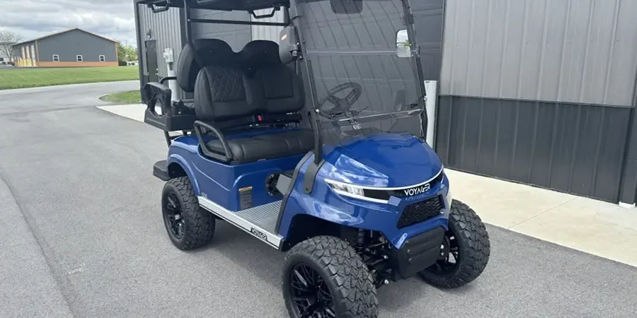 A blue lifted golf cart with off-road tires, front-facing seats, and a windshield parked outside a dealership, showcasing a custom golf cart upgrade ideal for family and recreational use in Indianapolis.